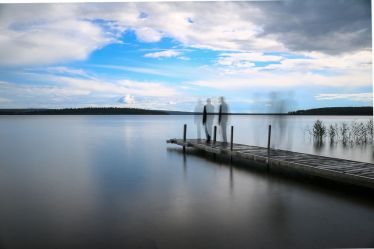 Silhouette of a man walking on a pier at the lake