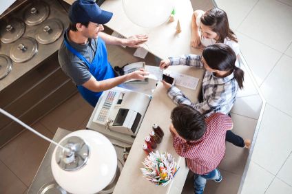 Waiter Giving Receipt To Female Customer Standing With Family